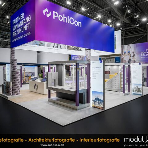 Professionelle Messestandfotografie des modernen PohlCon Messestandes auf der BAU 2025 in der Messe München. Aufnahme nach Messeschluss ohne Publikum, die das gelungene Lichtkonzept und die Standarchitektur hervorhebt.
