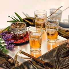 Ein Tablett mit gefüllten orientalischen Teegläsern, einer Zuckerdose und einem Lavendelzweig zur Dekoration