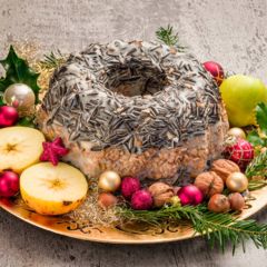 Eine weihnachtliche Vogelfuttertorte mit Kernen, Nüssen, Äpfeln, Sonnenblumenkernen und Ilex als Dekoration