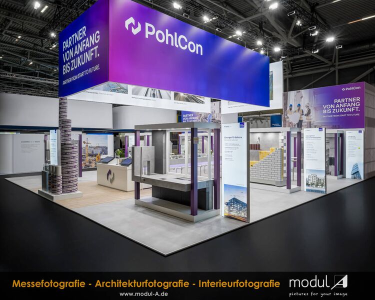Professionelle Messestandfotografie des modernen PohlCon Messestandes auf der BAU 2025 in der Messe München. Aufnahme nach Messeschluss ohne Publikum, die das gelungene Lichtkonzept und die Standarchitektur hervorhebt.