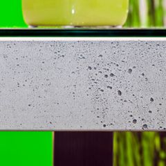 Eine Tischplatte aus Beton auf der eine grüne Vase steht
