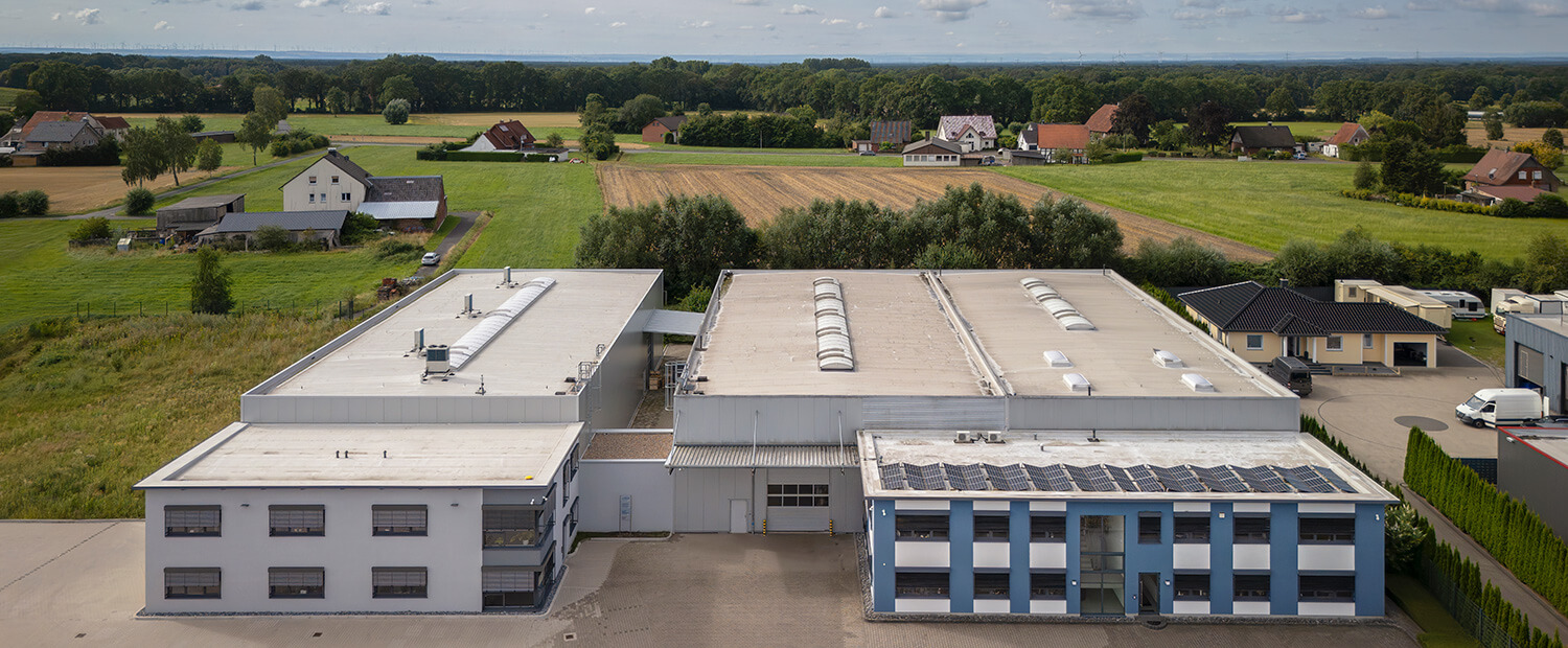 Drohnenaufnahme einer Gewerbeimmobilie mit angrenzender Produktionshalle und Lagerhalle