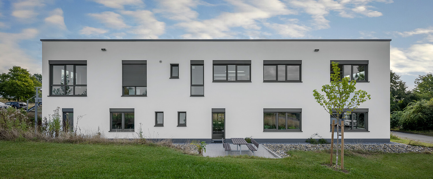 Architekturaufnahme einer Gewerbeimmobilie mit Grünstreifen und Sitzecke