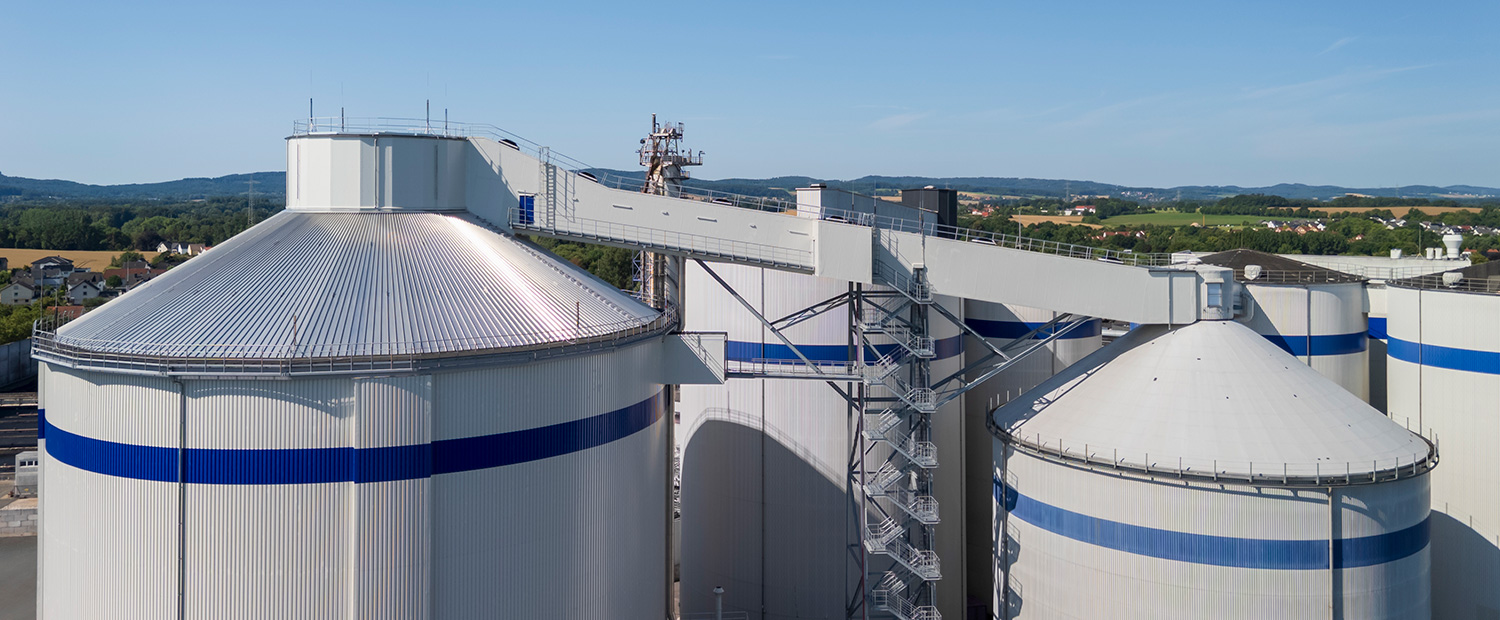 Die Drohnenaufnahme einer Gewerbeimmobilie mit Lagertanks und Wendeltreppe aus Metallbau.